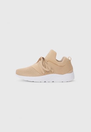 Beige sportieve schoenen met een bovenwerk van mesh, zachte textiele accenten, elastische veters en een witte zool met textuurdetails.