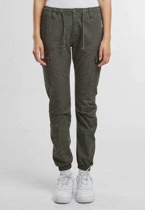 Pantaloni cargo di colore verde oliva, realizzati in tessuto leggero, con polsini elasticizzati, vita con cordoncino e due tasche laterali. Sneakers bianche visibili.