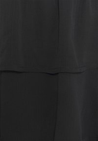 Svart lager av tyg med en strukturerad yta. Har en mjuk, flödande design med en lätt lyster och släta kanter.