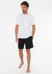 Vit bomull t-shirt med kort ärm, matchad med svarta bomullsshorts. Enkelt design, avslappnad passform, inga synliga mönster eller accenter.