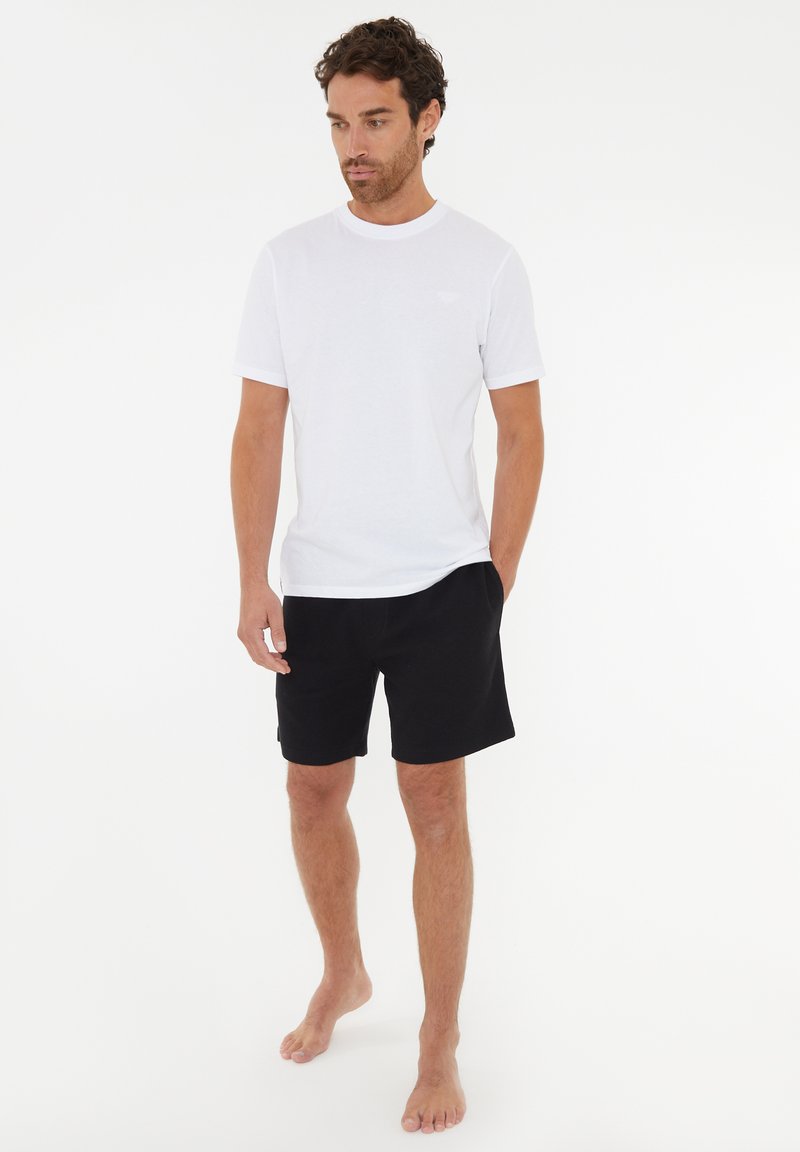 Vit bomull t-shirt med kort ärm, matchad med svarta bomullsshorts. Enkelt design, avslappnad passform, inga synliga mönster eller accenter.