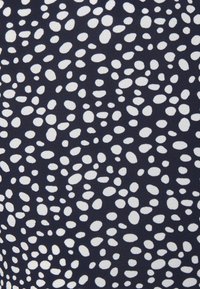Tejido de color azul marino con una textura palpable que presenta un patrón de piedras blancas dispersadas en varias tamaños. El patrón está distribuido de manera uniforme a lo largo del material.