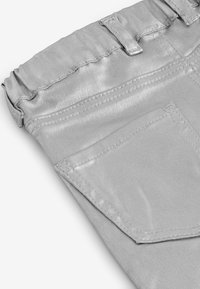 Silver metallisk tyg med en mjuk textur, elastisk midja och en bakficka med synlig sömdetalj.