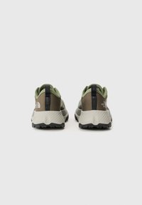 Baskets de sport vertes et grises avec une tige texturée, des accents noirs au niveau du talon, et une semelle en caoutchouc prononcée avec un motif de treads.