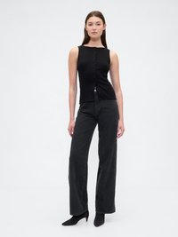 Top de alças negro canelado com fecho de botão na frente, combinado com jeans de ganga escura de cintura alta, com um corte solto e ligeiro efeito flare.