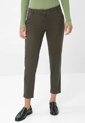 Olivgrüne Hose aus einem glatten Stoff, mit Knopfverschluss, geradem Schnitt und umgenähtem Knöchellang. Kombiniert mit schwarzen Loafers.