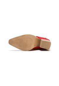 Zapato rojo con un acabado texturado, suela plana y una suela exterior de goma en un marrón claro y suave, que presenta surcos horizontales para mayor tracción.