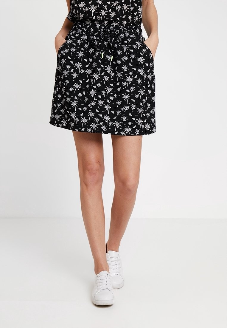 Vestido negro con estampado de palmeras blancas, cintura con cordón ajustable y bolsillos laterales. La tela parece ligera y casual.