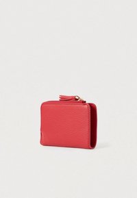 Compact red textured leather wallet with gold zipper and tassel detail, standing upright on a plain light background.