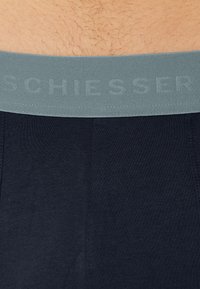Zwarte boxershort met een grijze elastische tailleband, voorzien van reliëf brandlettering. De stof lijkt soepel en biedt een aansluitend ontwerp.