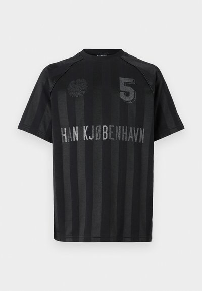 T-shirt preta de mangas curtas com riscas verticais, um emblema texturizado no lado esquerdo do peito, e o texto "HAN KØBENHAVN 5" em prateado.