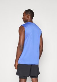 Ärmelloses blaues Sportoberteil aus atmungsaktivem Material, mit Rundhalsausschnitt und glatter Oberfläche, kombiniert mit schwarzen Shorts.
