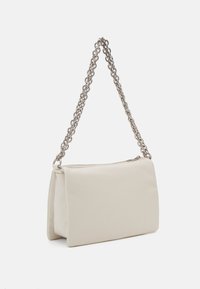 Borsa sintetica crema con forma rettangolare, lati piatti e tracolla in catena argentata. Texture liscia con chiusura a zip sulla parte superiore.