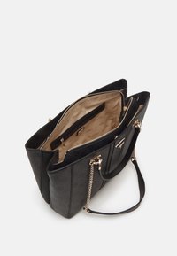 Sac cabas noir texturé avec poignées en chaîne dorée, doublure intérieure beige imprimée du nom de la marque, et plusieurs compartiments zippés ouverts.