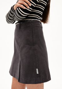 Grijze corduroy rok met een uitlopende vorm, voorzien van zijslits en een klein merklabel op de zoom. De stof heeft een geribbelde textuur.