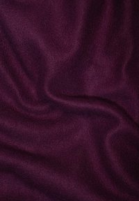 Ciemnofioletowy materiał o miękkiej, gładkiej teksturze, pokazujący łagodne fale i nierówne zagięcia, typowe dla lekkiej wełny lub materiału polarowego.