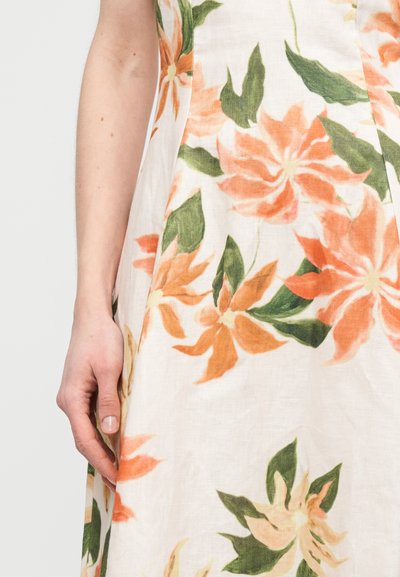 Φλοράλ φόρεμα με υφή λινέλαιο, που διαθέτει μεγάλα πορτοκαλί και πράσινα λουλούδια σε ανοιχτό μπεζ φόντο, με εφαρμοστή γραμμή και λεπτομέρεια στη πλευρική ραφή.