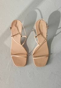 Beige platte sandalen met dunne, gekruiste banden, vierkante neusdesign, gladde textuur en verstelbare enkelgesp. Geschikt voor casual draagstijl.