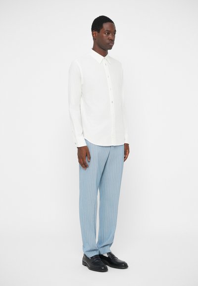 Witte button-up shirt, lichtblauwe gestreepte broek, zwarte schoenen. Slim fit, lange mouwen, minimalistisch design, gladde textuur.