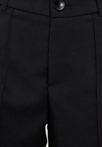 Zwarte broeken van gladde stof, met een knoopsluiting, plooien en zijzakken, met een getailleerde pasvorm en scherpe kreukdetails.