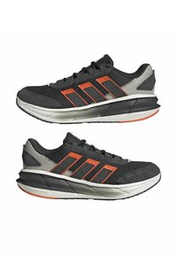Chaussures de sport noires en maille et matériau synthétique ; présentent des accents orange, une semelle texturée et un talon rembourré pour un soutien optimal.