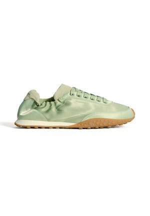 Groene satijnen sneaker met een ribbelrubberen zool, vetersluiting en elastische kraag. Beschikt over zachte textieldetails en een gebogen silhouet.