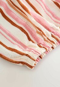 Tissu avec des rayures horizontales rose, blanc et marron et un détail élastique froncé le long du bord.