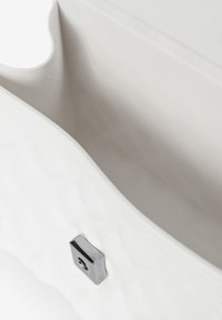 Witte, gequiltte tasinterieur met een zachte textuur, ronde opening en een zilveren magneetsluiting.