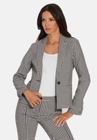 Zwart-wit geblokte blazer met een slim fit, enkele knoopsluiting en notch revers. Gelaagd stof met bijpassende geblokte broek.