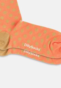 Korallefarbene Socken mit goldenen Punkten, die eine weiche Textur aufweisen. Enthält das "DillySocks"-Branding in Weiß an den Bündchen.