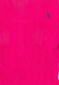 Tissu maille torsadée rose vif avec un petit logo brodé d’un joueur de polo noir en haut à droite.