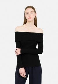 Top nero a spalle scoperte in maglia a coste con maniche lunghe, caratterizzato da un collo ripiegato e tessuto testurizzato. Il modello si trova contro uno sfondo bianco.