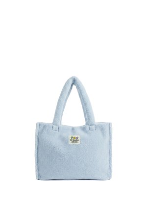 Bolsa tote de forro polar suave color azul claro con dos asas y una pequeña etiqueta con parche que dice "On Vacation" con iconos de palmeras.