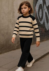 Beiges geripptes Sweatshirt mit schwarzen Streifen und schwarzen Raglanärmeln, kombiniert mit schwarzen weiten Hosen und weißen Sneakern. Lässiger urbaner Look.