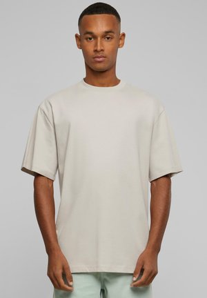 Light grey oversized t-shirt with short sleeves, round neckline, and smooth texture. Simple design without patterns or hardware details.