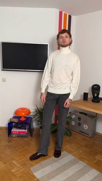 Fehér garbó bordázott mandzsettákkal, sötétszürke farmerrel párosítva. A szettet sötétbarna cipő és kéztetoválások egészítik ki.