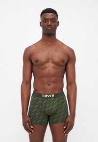 Gröna boxerkalsonger med ett mönster av Levi's logotyp över hela ytan. Tillverkade av ett mjukt, stretchigt tyg, med ett kontrasterande svart midjeband.
