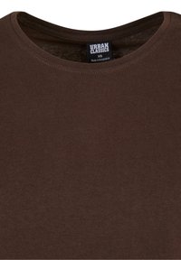 T-shirt marron col rond affichant l'étiquette de la marque Urban Classics et la taille XS, fabriqué au Bangladesh, à l'intérieur du col.