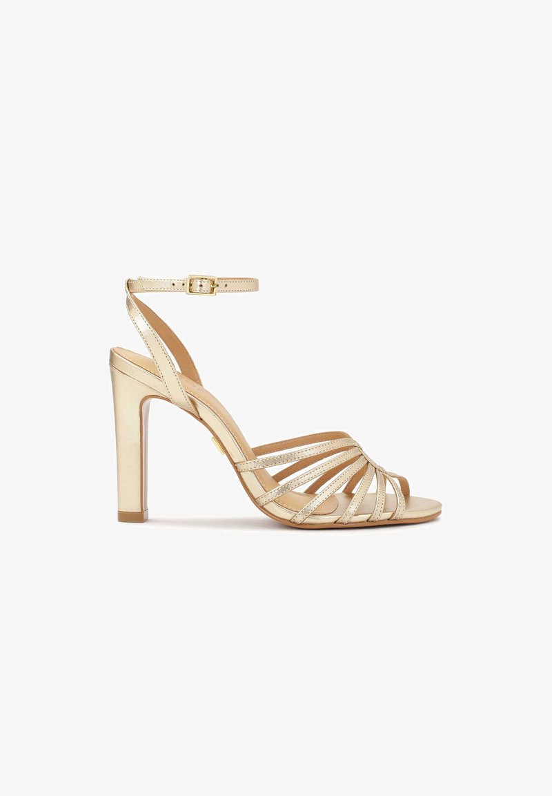 Strap-Sandal mit hohen Absätzen aus metallischem goldfarbenem Leder, mit einem Knöchelriemen und einem Blockabsatz. Offenzehendesign mit horizontalen Riemen.