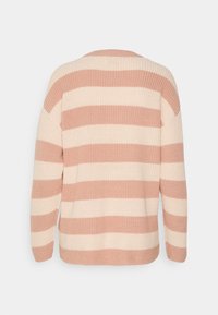 Pull en tricot rayé en rose doux et crème. Coupe large avec épaules tombantes et texture en côtes. Présente de larges rayures horizontales.