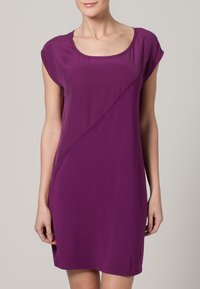 Lila avslappnad klänning med korta ärmar, rund halsringning och diagonala sömdetaljer. Tillverkad av mjukt, slätt tyg. Längd till mitten av låret.