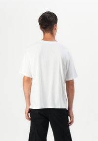 Hvid bomulds t-shirt med en afslappet pasform, korte ærmer og rund halsudskæring. Glat tekstur, ensartet design og ingen synlige grafikker.