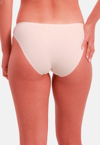 Vaaleanpunainen bikinialaosa, jossa on sileä pinta. Matala vyötärö ja minimaalinen takapeite, yksinkertainen vyötärönauha ilman näkyvää metalliosaa.