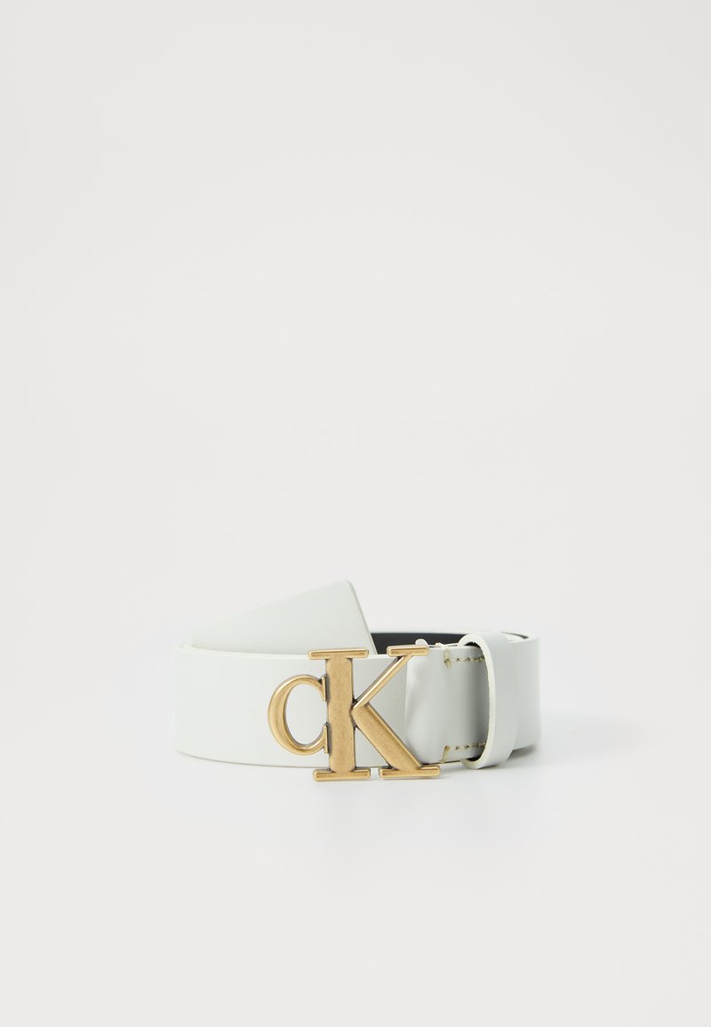 Cinturón de cuero blanco con hebilla de logo 'CK' en tono dorado, que presenta una textura suave y longitud ajustable. Diseño simple sin acentos adicionales.
