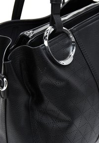 Zwarte leren handtas met een gequiltte textuur, zilverkleurige hardware accent en een ronde ringdetail nabij de bovenste ritssluiting.