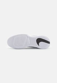 Semelle de chaussure de sport blanche avec une texture antidérapante, présentant un grand motif en forme de swoosh noir et un motif de traction circulaire pour une meilleure stabilité.