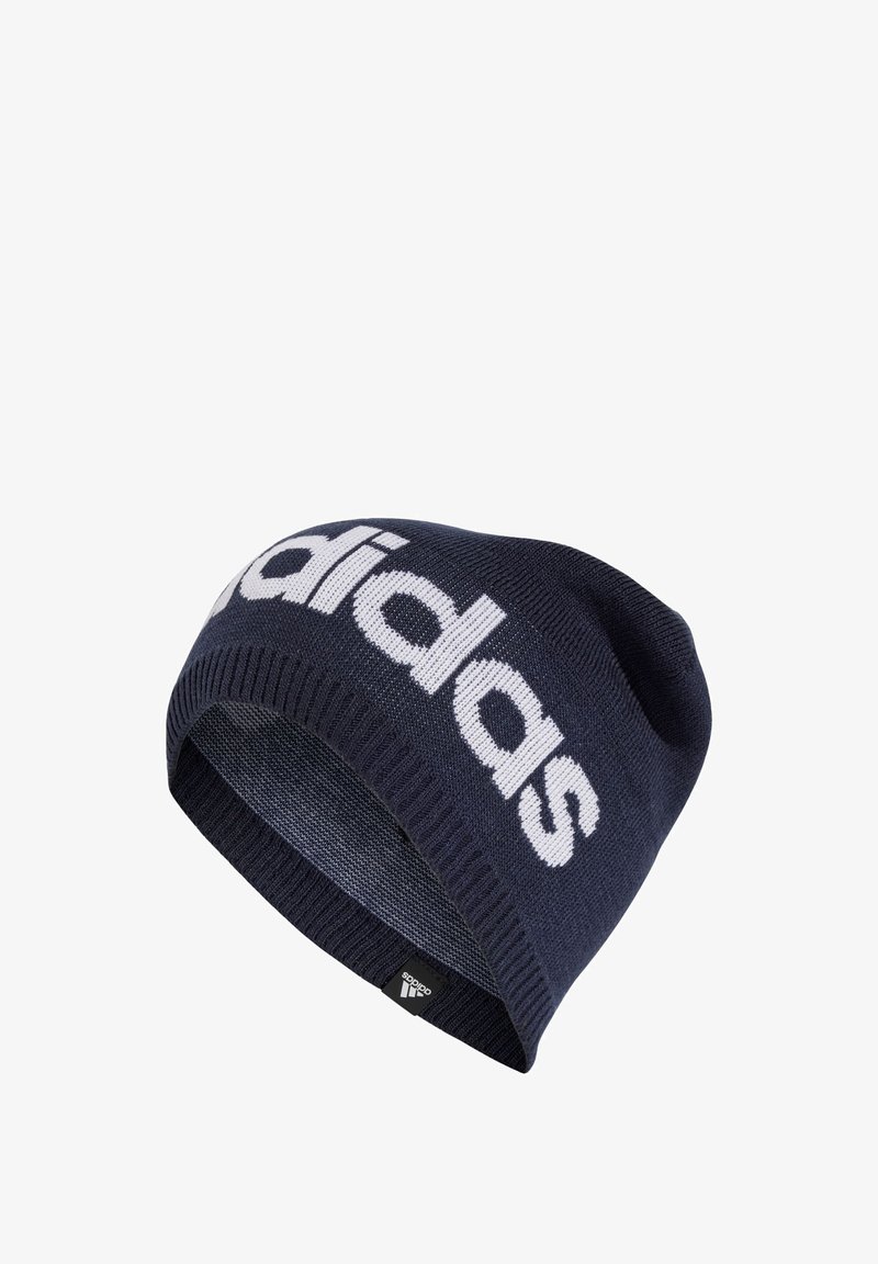 Navy knit beanie with a white "adidas" logo. Features a ribbed cuff and smooth texture. Includes a small black brand tag at the hem.