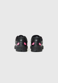 Schwarze Nike-Sneaker mit pinken Akzenten, aus Mesh- und synthetischen Materialien, abgerundeter Ferse, strukturiertem Sole und auffälligen Ausschnitten im oberen Teil.