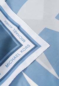 Lys blå silkescarf med geometriske mønstre, en hvid kant og brandteksten "MICHAEL KORS" i et gentaget design.