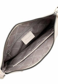 Interno di una borsa in pelle beige chiaro con una fodera grigia a motivo, dotata di una tasca con zip e due scompartimenti per l'organizzazione.